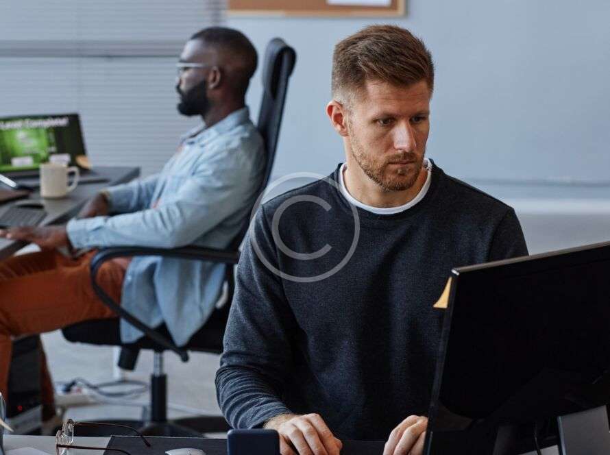 Two men working on computers in a modern office setting.