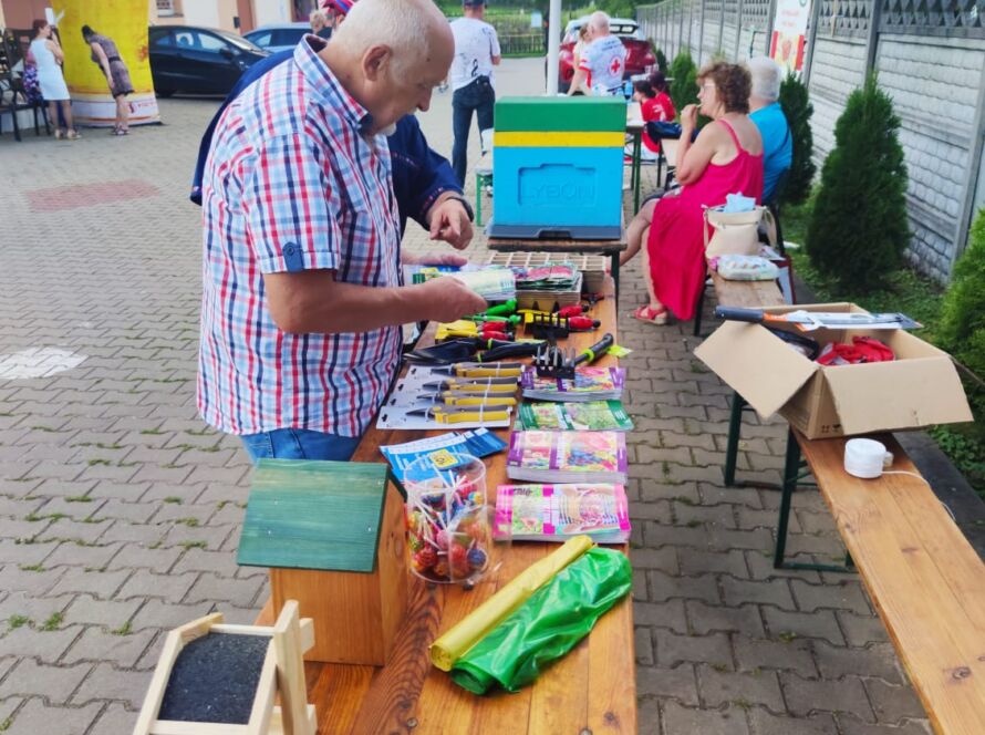 Mężczyzna ogląda narzędzia na drewnianym stole na zewnątrz przy parasolu