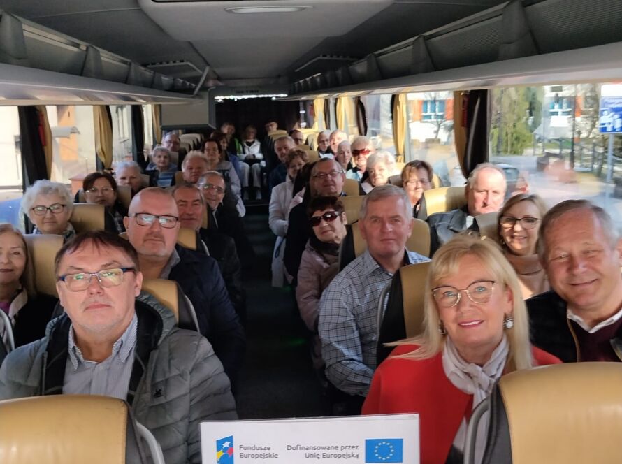 Grupa ludzi siedzących wewnątrz autobusu trzymająca certyfikat.