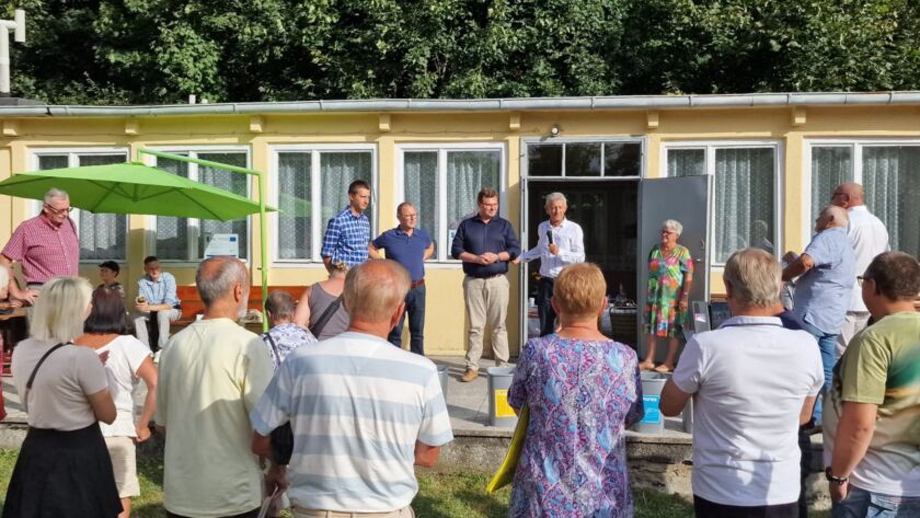 Grupa osób uczestnicząca w wydarzeniu na świeżym powietrzu przed budynkiem.