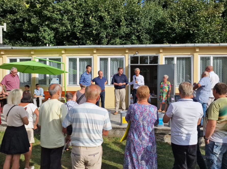 Grupa osób uczestnicząca w wydarzeniu na świeżym powietrzu przed budynkiem.