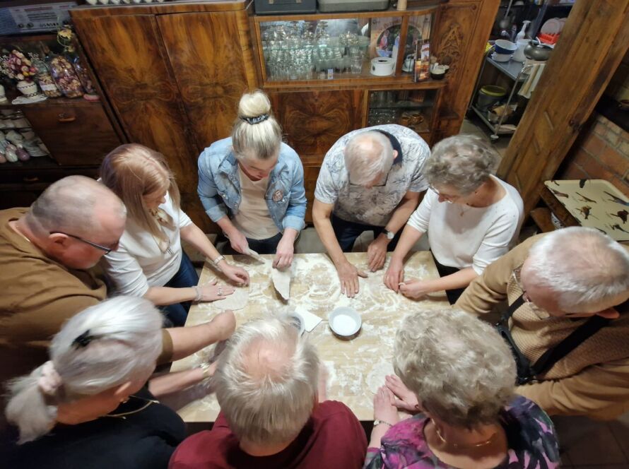 Group of people gathered around a table making dough.