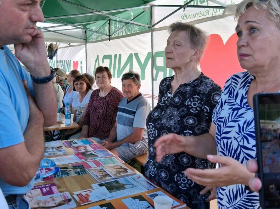 Osoby siedzące przy stole z materiałami edukacyjnymi na temat zdrowia.