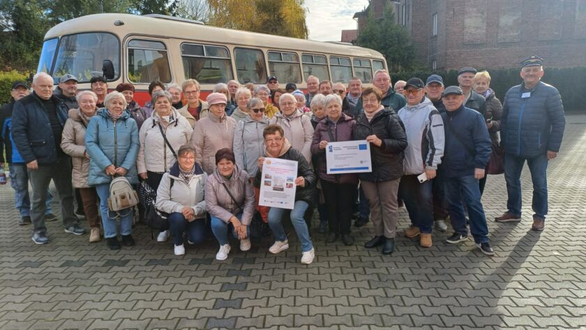 Grupa seniorów przed zabytkowym autobusem, wspólne zdjęcie wycieczki, jesienny dzień