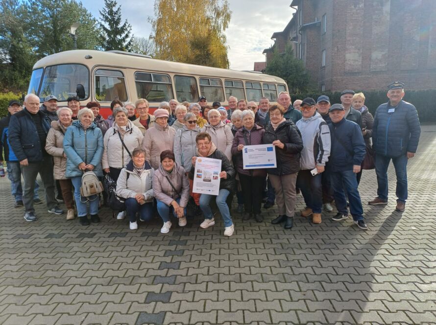 Grupa seniorów przed zabytkowym autobusem, wspólne zdjęcie wycieczki, jesienny dzień