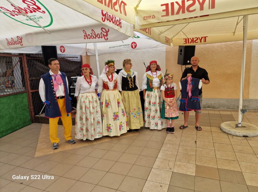 Grupa ludzi w tradycyjnych strojach ludowych pod parasolami