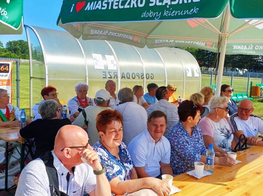 Grupa osób przy stole pod zielonym parasolem, Miasteczko Śląskie