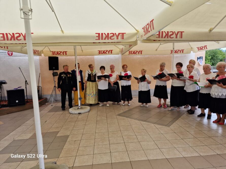 Grupa ludzi śpiewających na scenie pod namiotem.