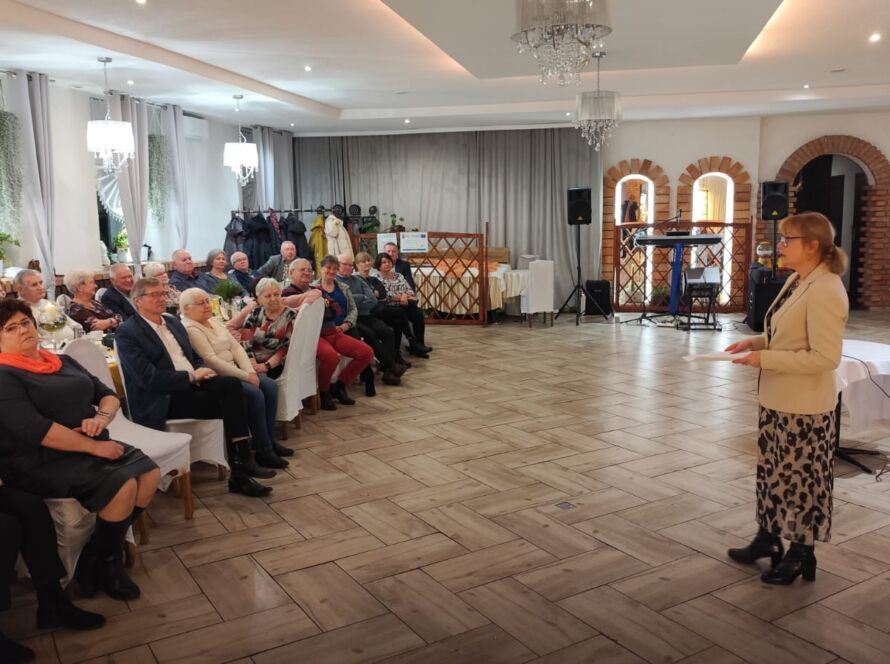 Prezentacja kobiety przed siedzącą publicznością w eleganckiej sali