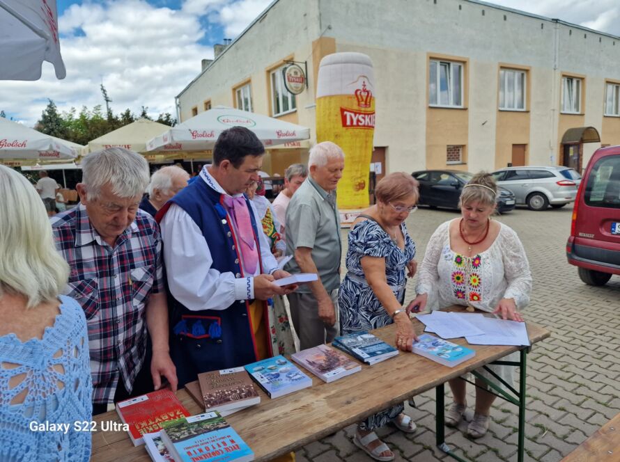 Grupa osób przegląda książki na stoisku plenerowym
