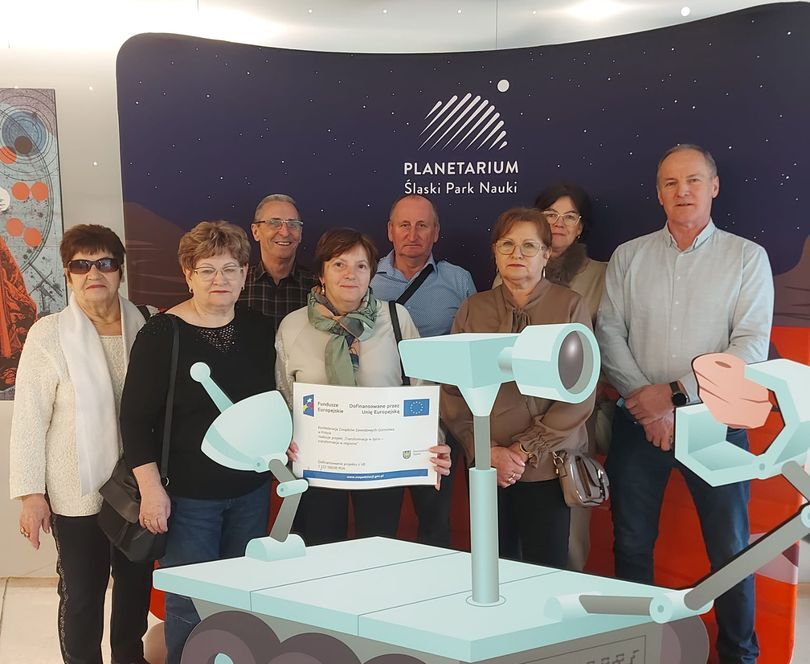 Grupa osób w Planetarium Śląskim w Śląskim Parku Nauki, stojąca przy makiecie łazika.