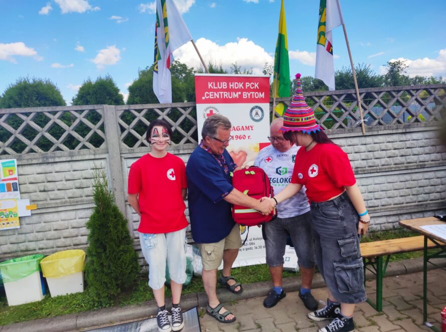 Grupa osób w koszulkach PCK na wydarzeniu z nagrodą.
