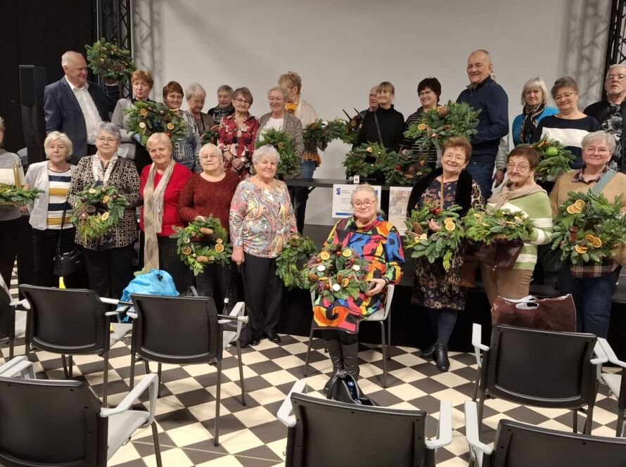 Grupa osób z wieńcami i ozdobami na warsztatach artystycznych